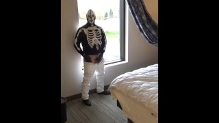 skeleton mask in pantyhose and jeans at hotel window