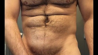 Hairy muscle stud flexing and stroking cock in public restroom
