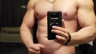 Big muscled hunk cums in front of mirror