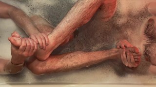 Two hairy guys caress each other in a bubble bath, do feet massage, piss and cum from handjob