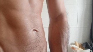 Muscular boy contracts muscles and penis in bathroom