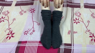 Girl in gray long socks on her legs caresses herself in bed