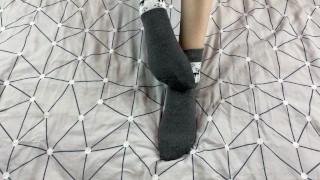 Girl with long legs caresses her feet in gray New Year socks with deer