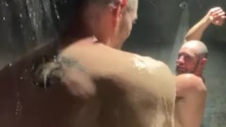 Beefy men shower together in gym locker room