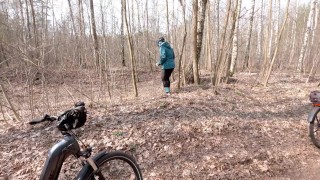 Early spring on bike pissing in the forest near the busy road