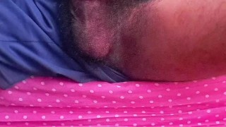 magrelo e pentelhudo sentado na cama batendo punheta com bermuda de futebol e gozando muito