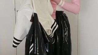 Putting on latex schoolgirl uniform shirt over rubber skirt, blouse, latex layers