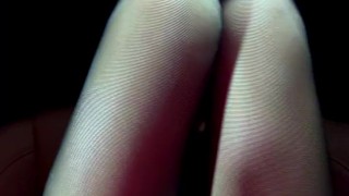 The girl lifts her skirt in the car and shows her black stockings