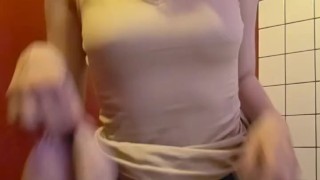 Charming girl takes off her bra from under her T-shirt
